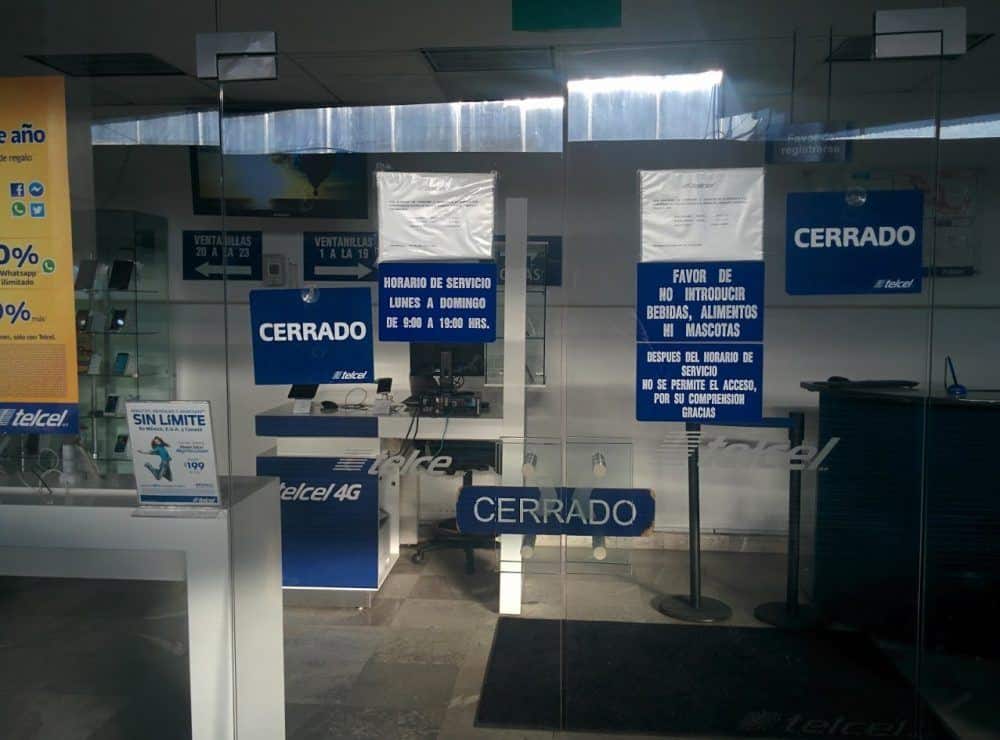 Outside of a store with Telcel branding at Mexico City airport. Signs saying "cerrado" (closed) are visible on the door, and the lights are turned off inside.