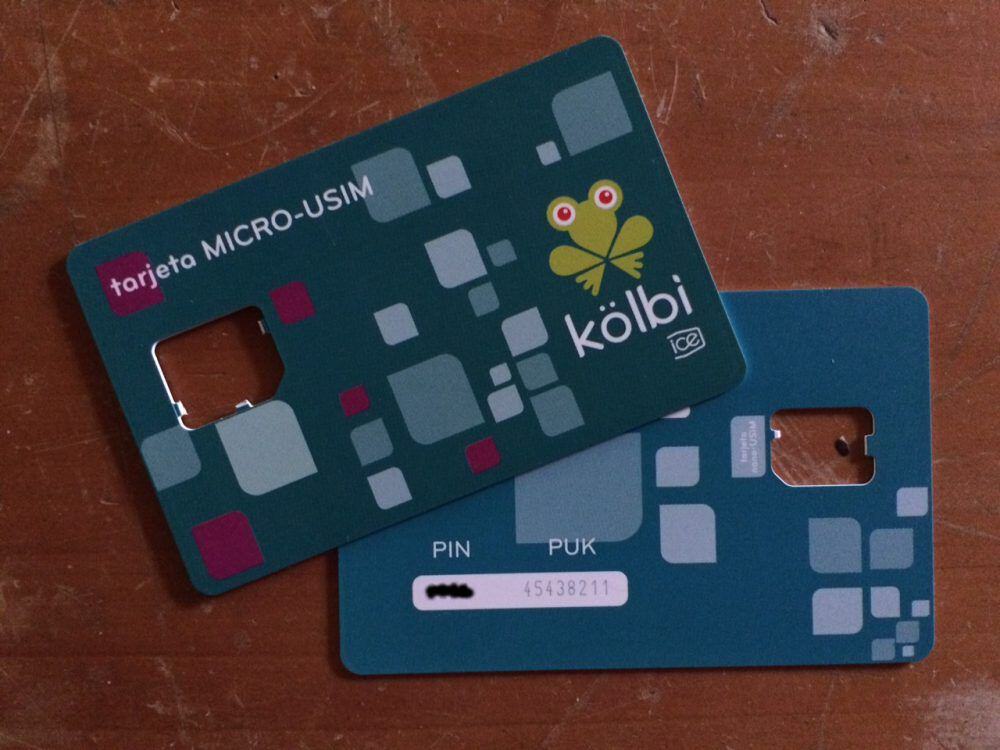 Two plastic SIM card packets with Kolbi branding and empty cutouts for the SIM cards, sitting on a scratched table.