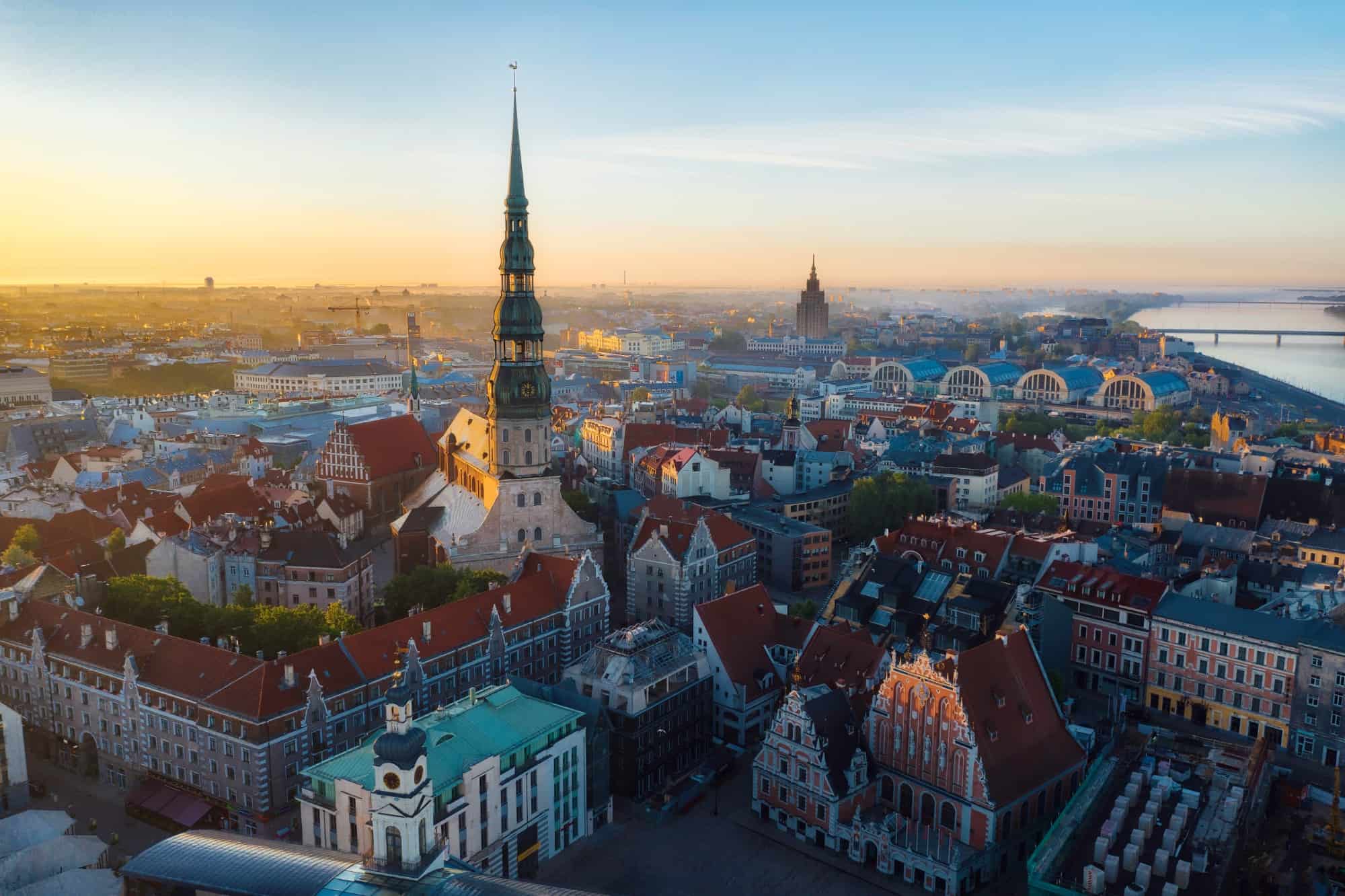 Aerial view of downtown Riga, in Latvia, at sunrise. Foreground is dominated by a large church spire. River visible in the distance.