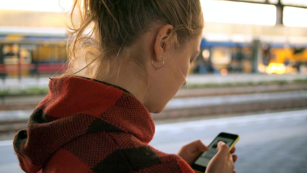 Woman using phone on train platform