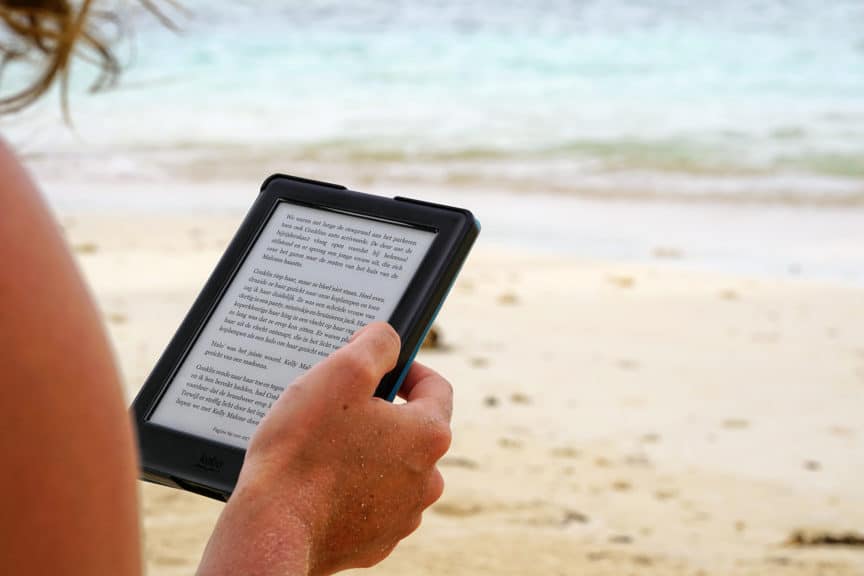 Woman reading Kindle-e-reader on beach