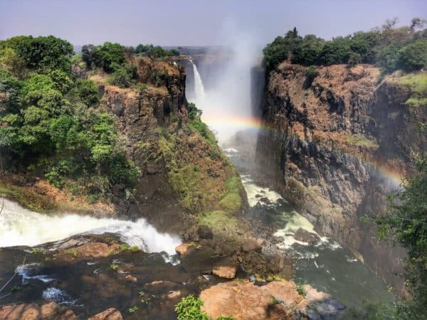 View of Victoria Falls with a rainbow caused by the waterfall