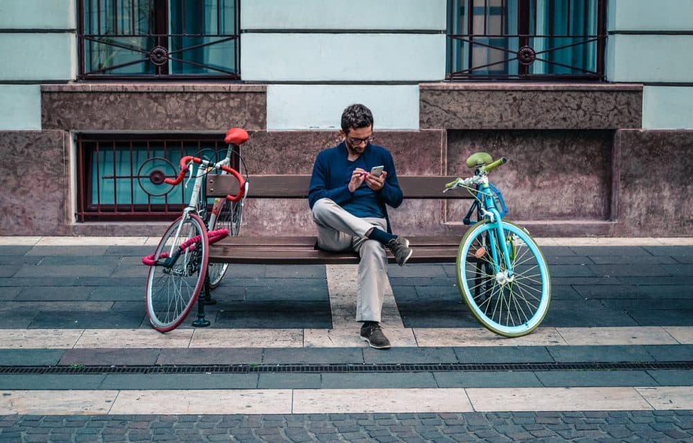 Man looking at phone while sitting on bench