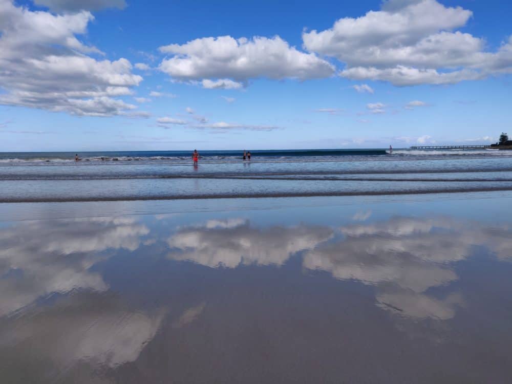 Smooth beach with reflections of clouds overhead, Australia