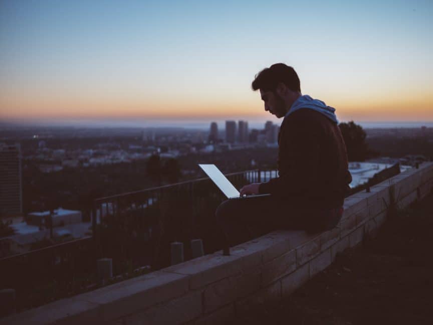 Man on laptop overlooking city