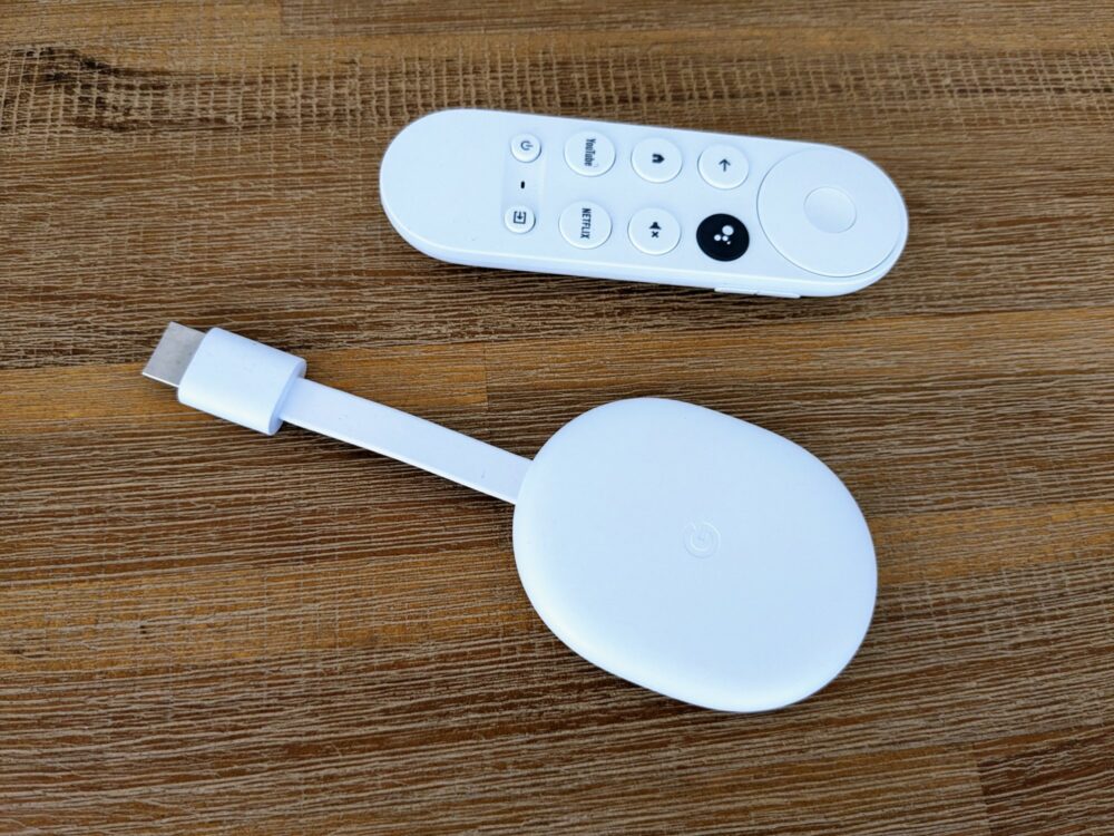 Chromecast with Google TV and remote sitting on a wooden table