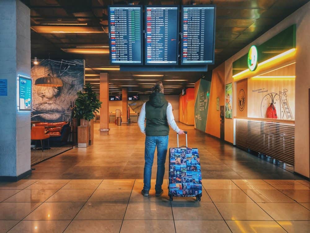 Man with suitcase looking at fight information screens