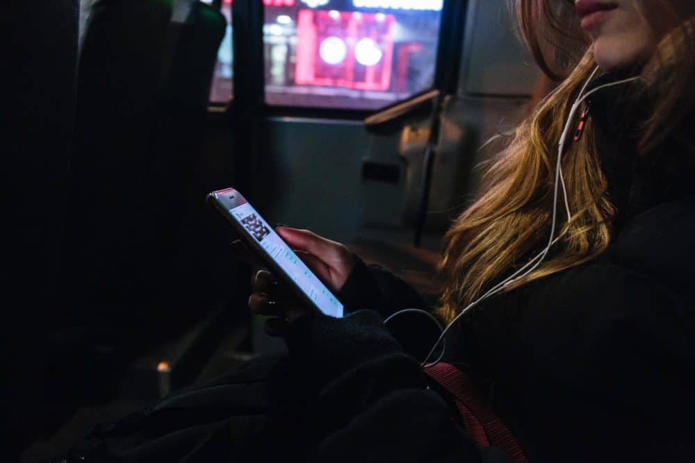 Woman on bus with earbuds and phone