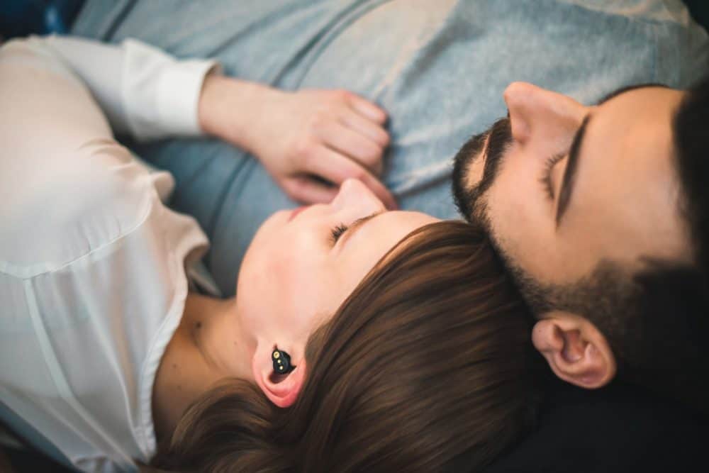 Couple in bed, woman wearing QuietOn earbuds