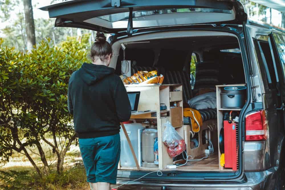 Man using laptop at back of campervan