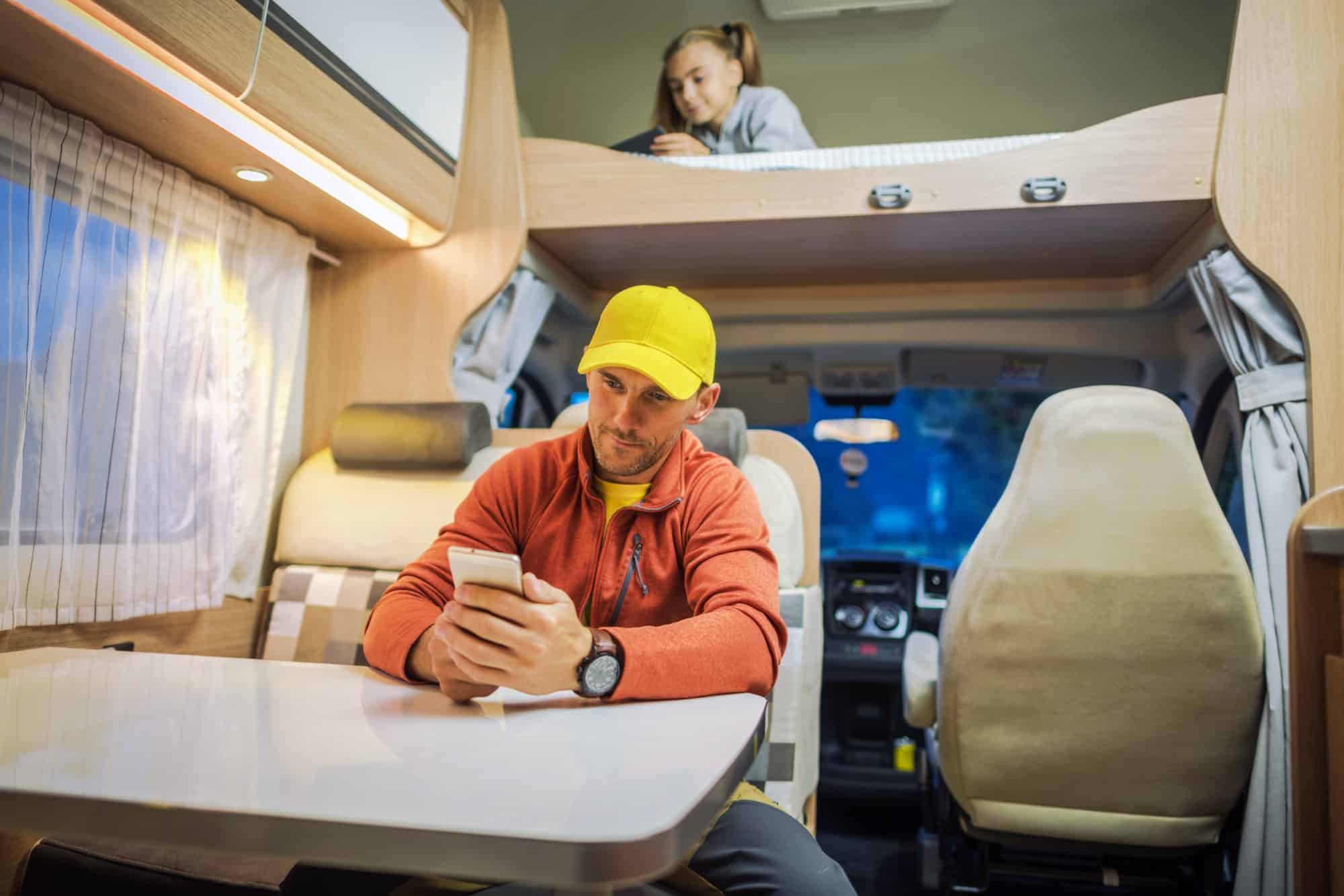 Man and girl using mobile devices inside RV