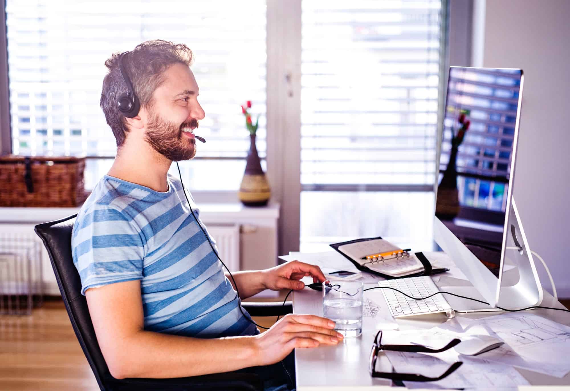 Man sitting in front of computer, working from home and wearing headphones