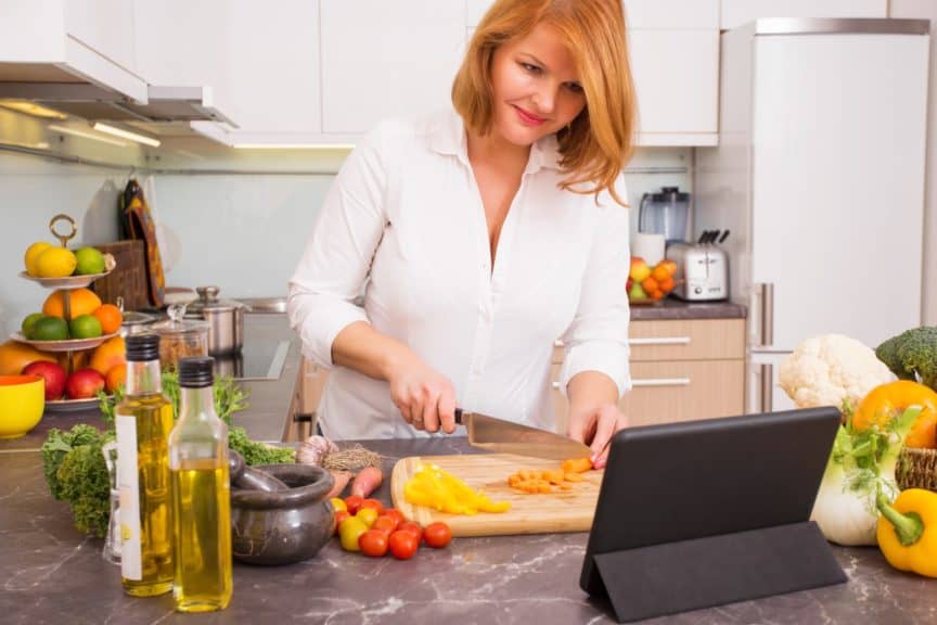 Woman cutting vegetables in kitchen looking at iPad on stand.jpg