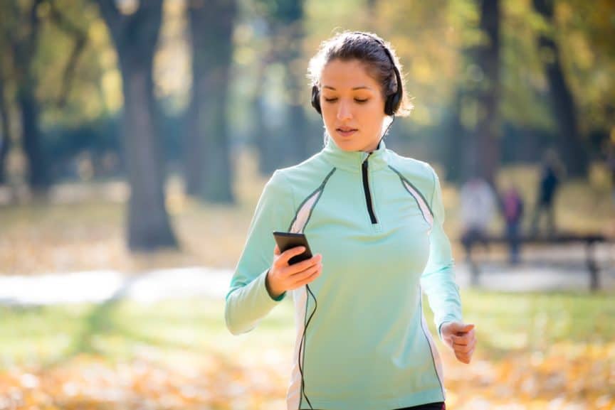 Woman runner looking at phone in park
