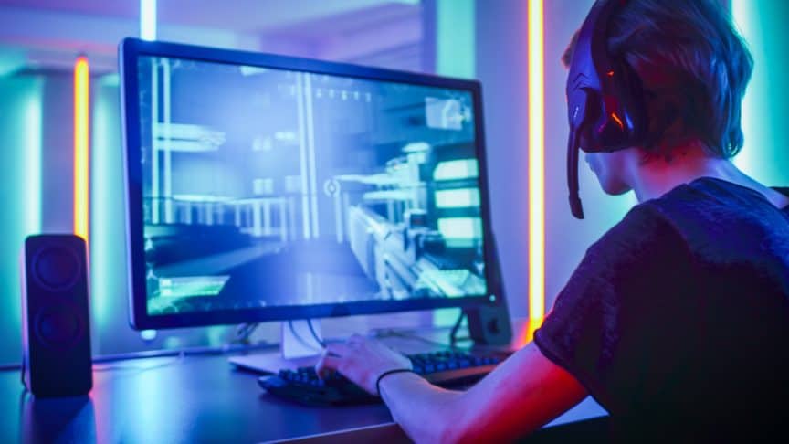 Young man wearing headset playing action computer game