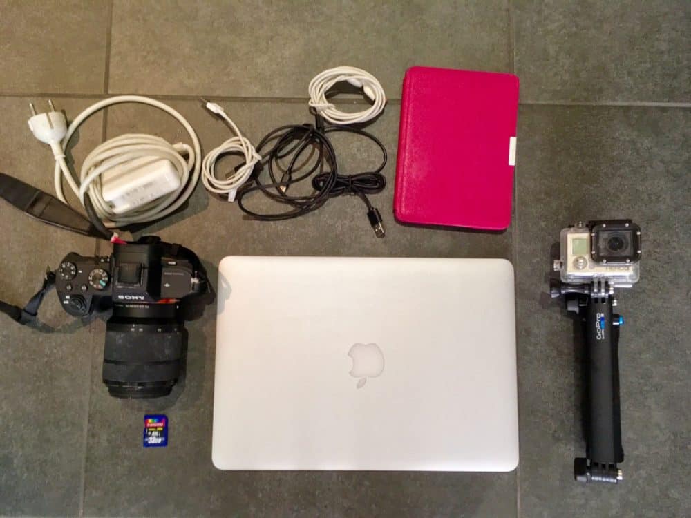 Laptop, cameras, Kindle, and chargers on a floor