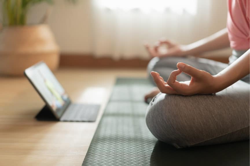 Person doing yoga in front of tablet computer