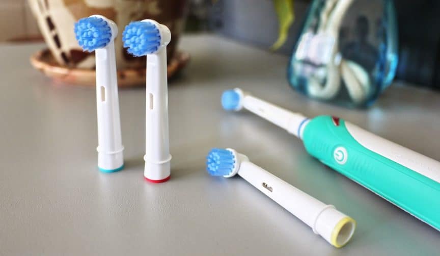 Electric toothbrush and three spare toothbrush heads sitting on counter