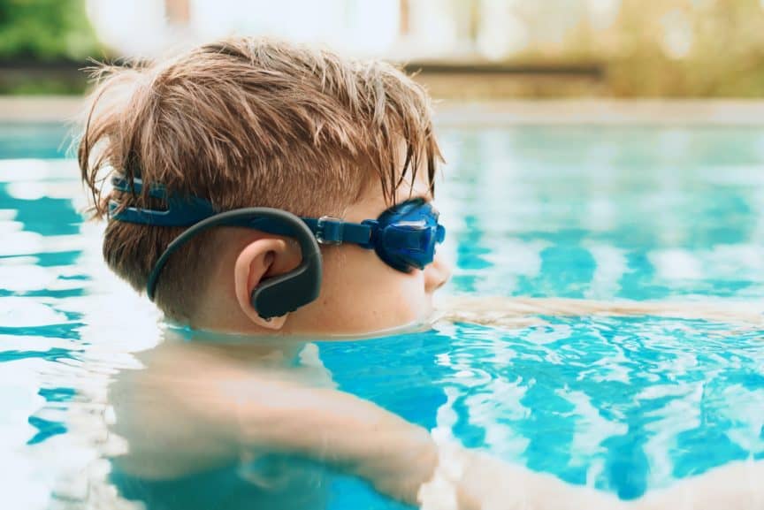 Boy wearing waterproof headphones in swimming pool