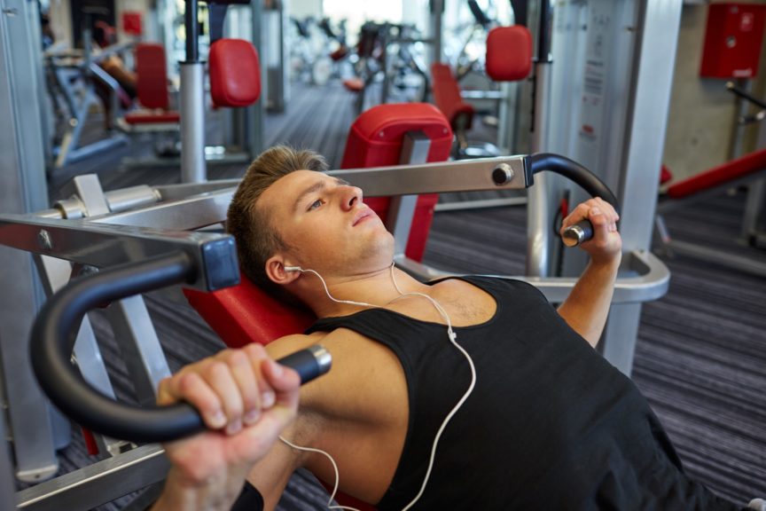 Young man working out in gym with earbuds in ears