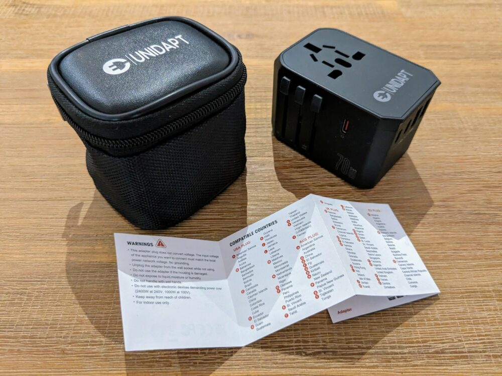 Unidapt travel adapter, travel case, and instruction booklet on a wooden table