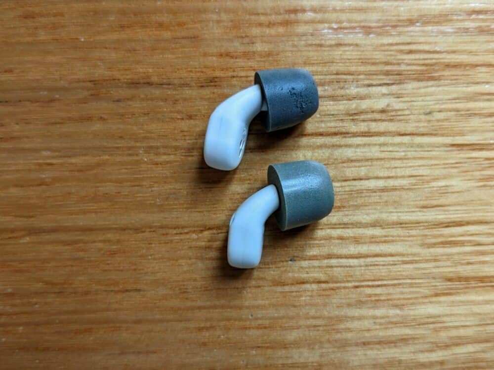 QuietOn 3.0 and 3.1 earbuds, one above the other, on a wooden floor