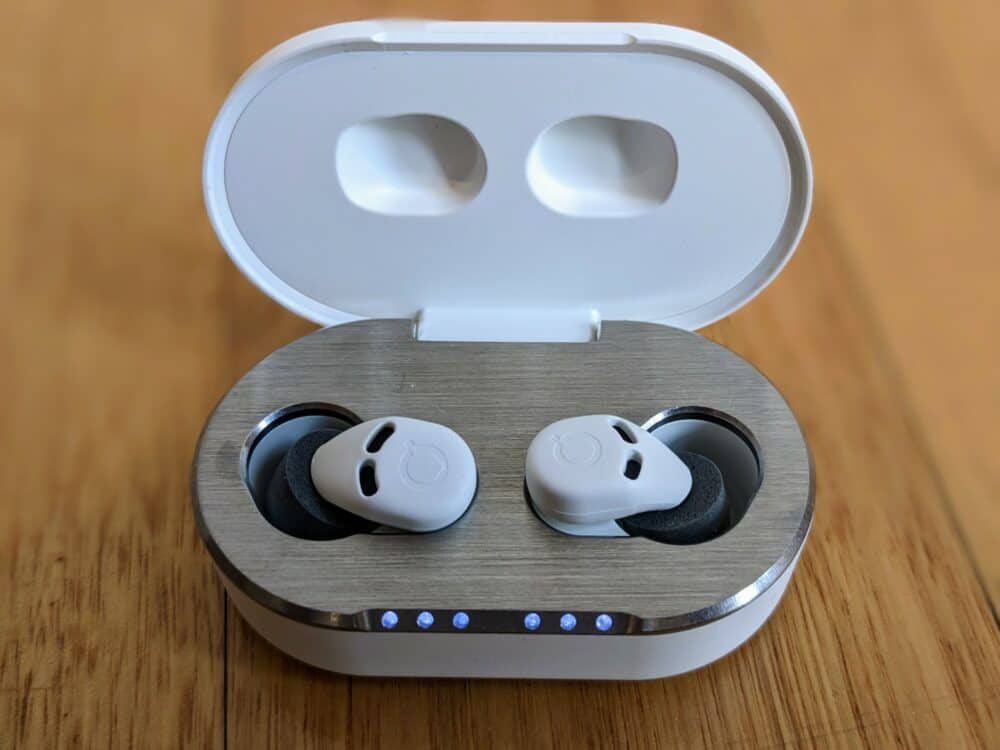 Closeup of QuietOn 3.1 earbuds in charging case on wooden floor