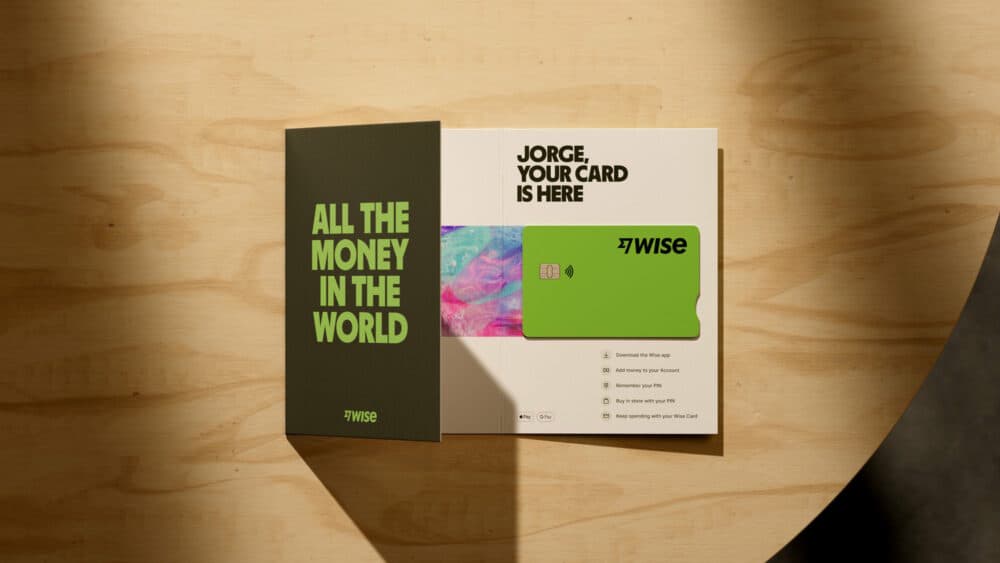 Mockup of Wise debit card in promotional packaging, sitting on a wooden table