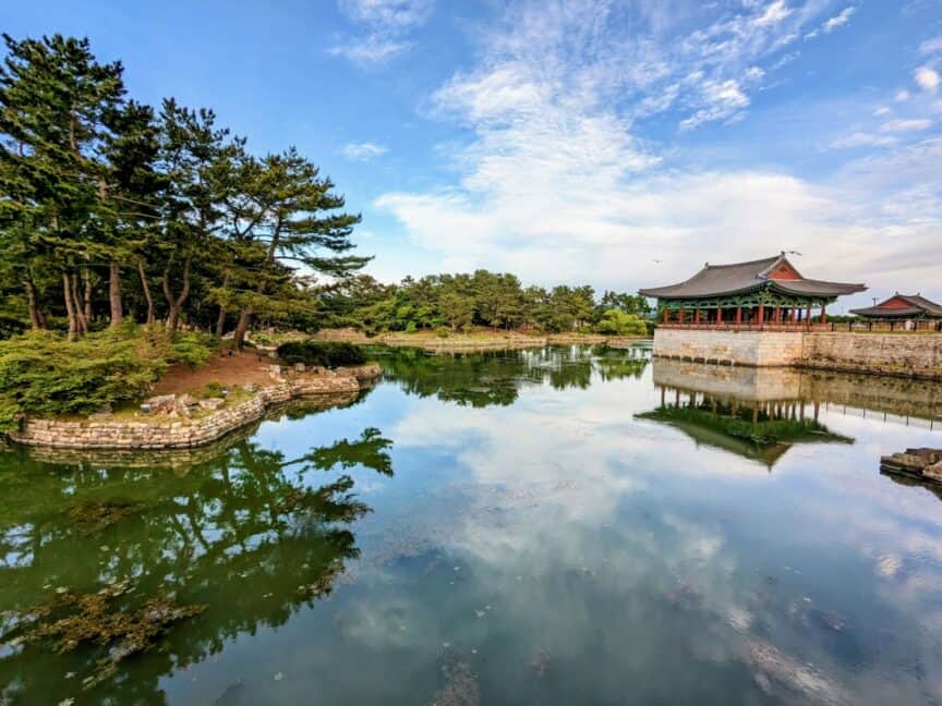 Buildings and pond at Donggung Palace, Gyeongju, South Korea, with blue sky in the background and trees alongside
