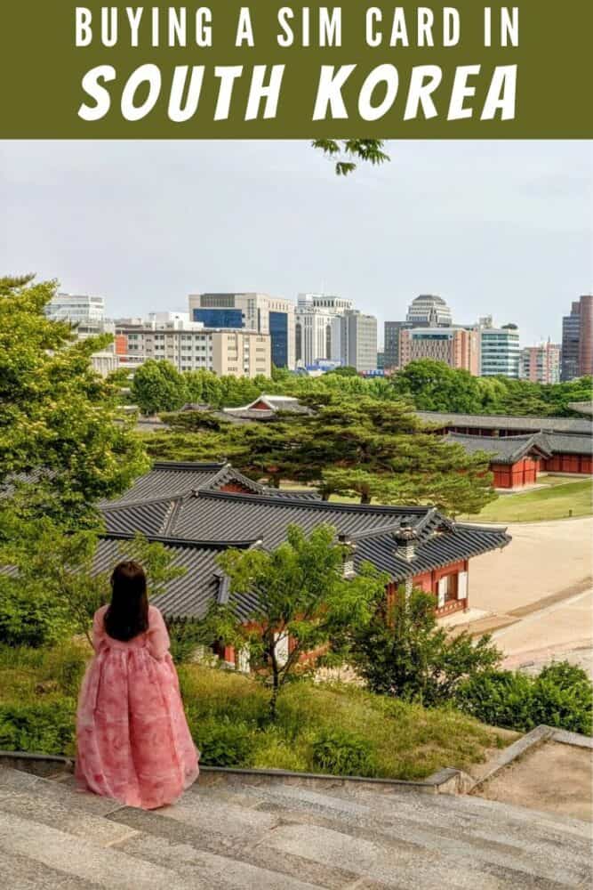 Woman in traditional hanbok dress standing on steps looking out towards buildings of Changgyeonggung Palace, with Seoul cityscape in background. Text "Buying a SIM Card in South Korea" overlaid at top