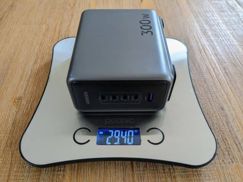 Ugreen 300W desktop charger laid on side, sitting on kitchen scales displaying 29.40oz. Wooden table underneath.