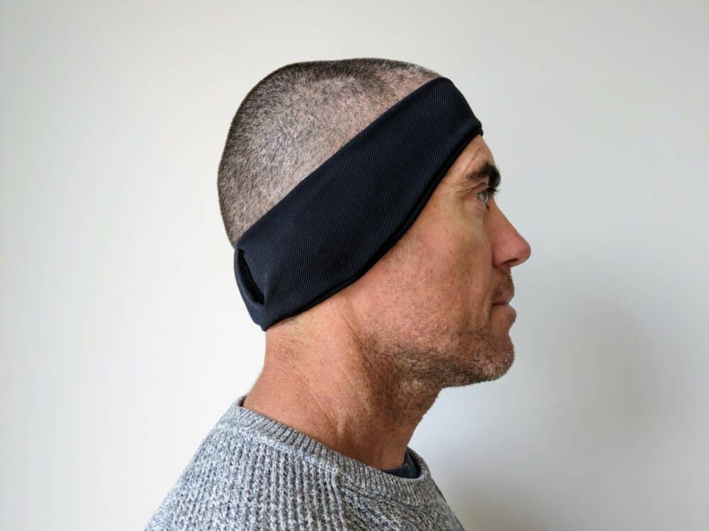 Side-on view of man wearing a black headband that covers his ears.