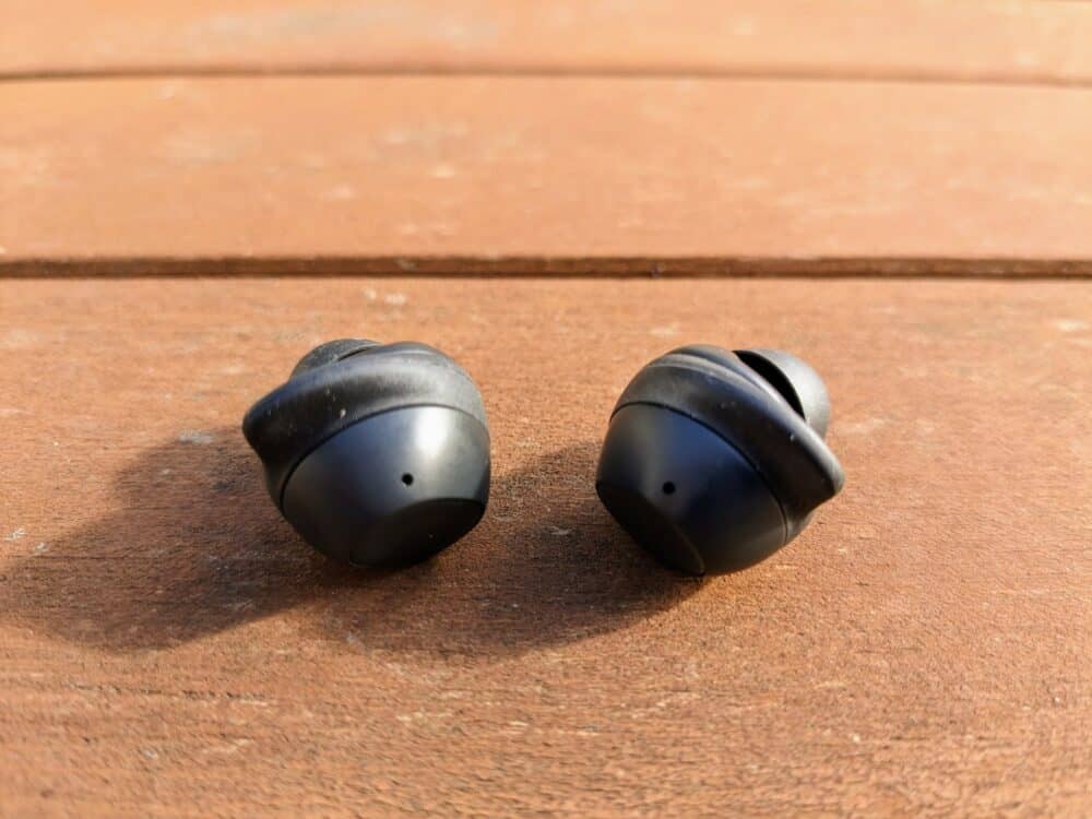 Two black earbuds sitting on a wooden table
