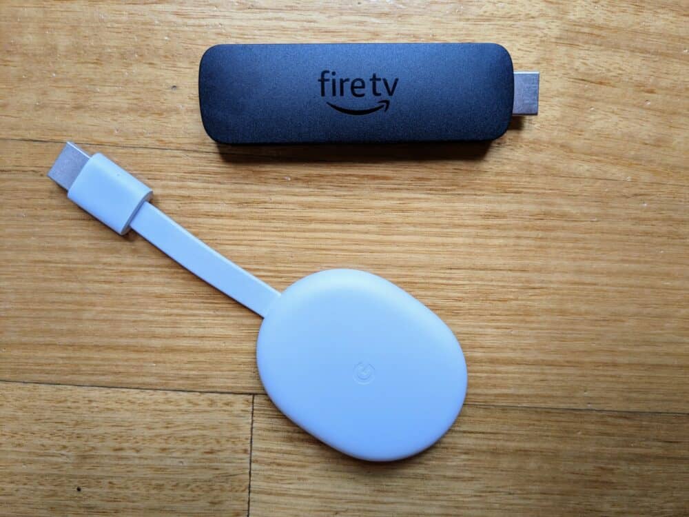 Amazon Fire TV Stick and Google Chromecast on a wooden floor