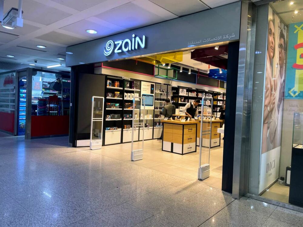 View from outside a phone store at an airport that has a Zain logo above the entrance.