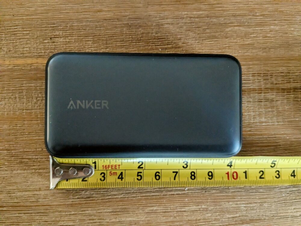 Anker power bank with measuring tape alongside, sitting on wooden table